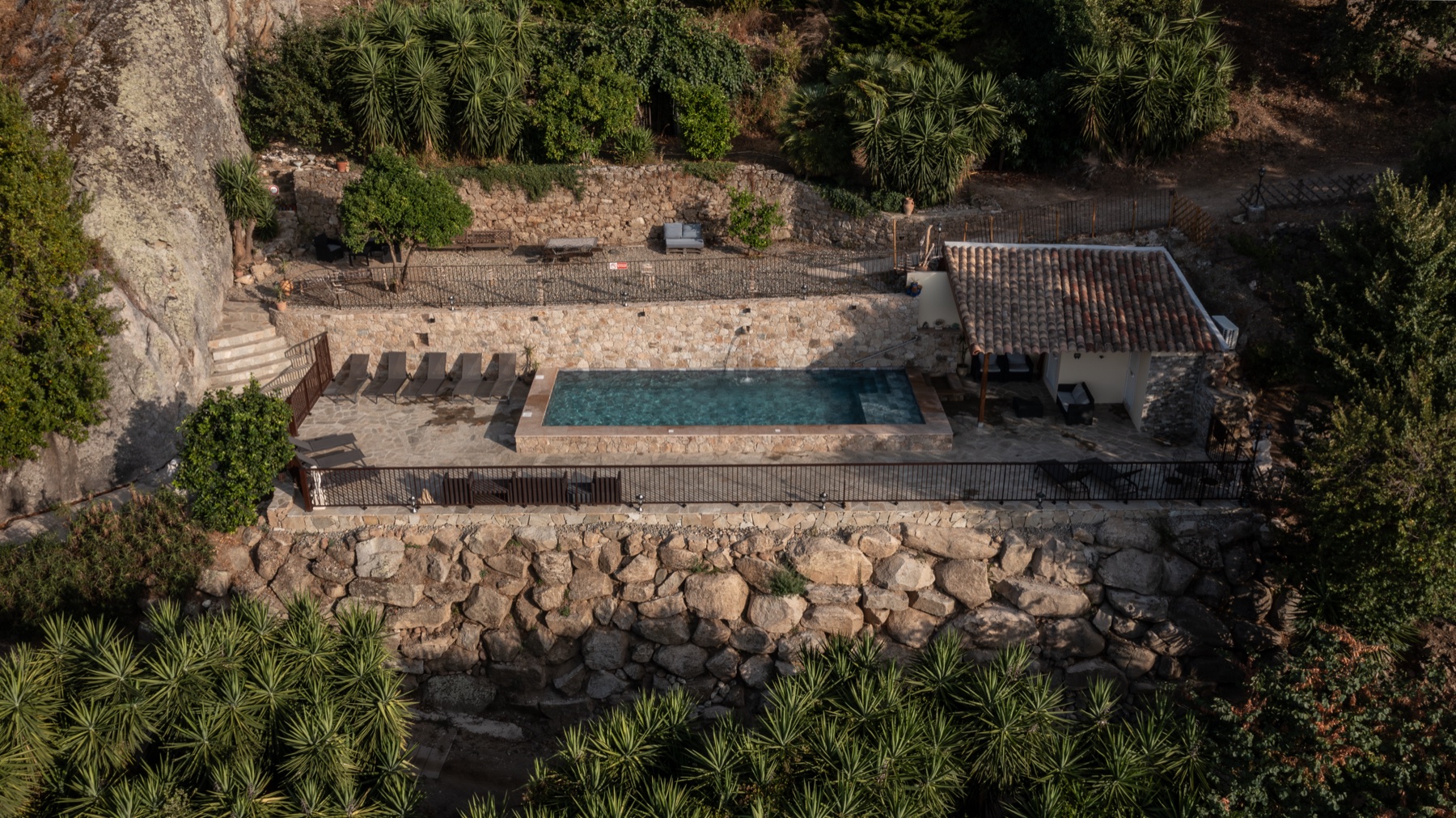 La piscine chauffée du domaine, bassin rectangulaire, cascade et plage immergée